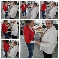 Seria zdjęć przedstawiających kobietę w czerwonej marynarce i mężczyznę w białej koszuli tańczących razem w sali z udekorowanymi stołami. Na różnych ujęciach widać ich w ruchu, trzymających się za ręce i śmiejących się. W tle stoły z jedzeniem oraz inni uczestnicy wydarzenia.