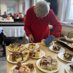 Uczestniczka ŚDS nakłada na telerze kawałki ciasta