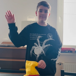 Chłopiec pozuje do zdjęcia trzymajać woreczek od gry Rummikub