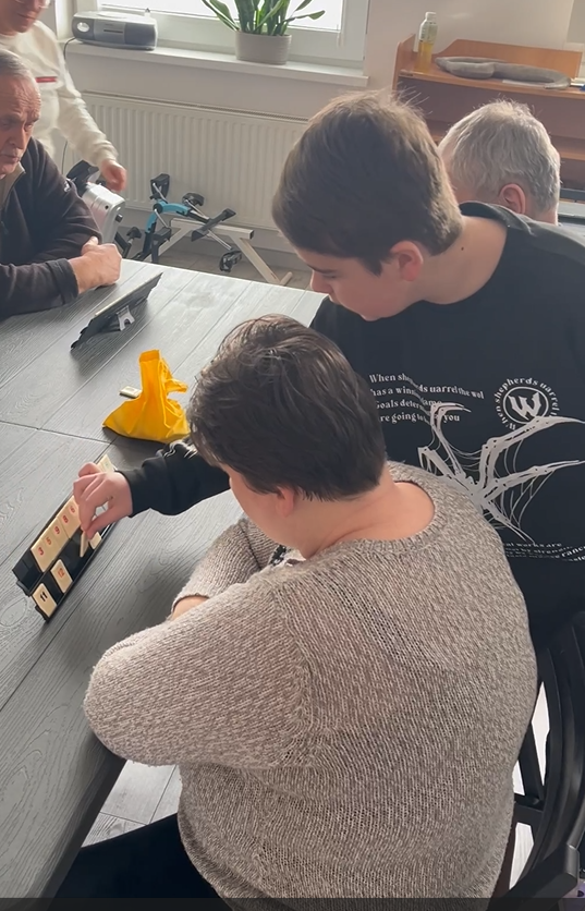 Chłopiec instruuje uczestniczkę ŚDS podczas gry w Rummikub