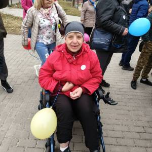 Uczestniczka ŚDS ubrana w czapkę, czerwoną kurtkę i z żółtym balonem w ręku pozuje do zdjęcia