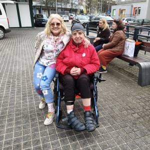 Dwie osoby pozują do zdjęcia, pokazując swoje kolorowe skarpetki