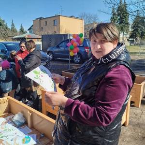 Uczestniczka ŚDS trzyma w ręku kartkę informacyjną na temat sadzenia