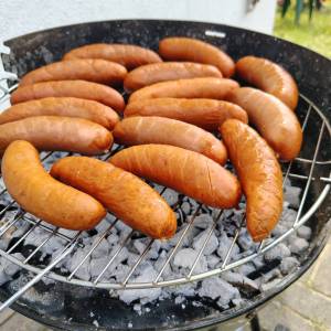 Zbliżenie naciętych kiełbasek na rozpalonym grillu