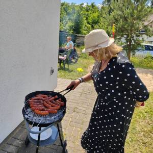 Uczestniczka ŚDS przerzuca kiełbaski na grillu