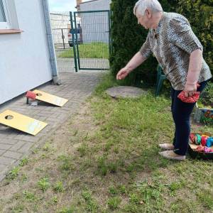 Uczestniczka ŚDS bierze udział w zabawie polegającej na rzucaniu woreczkiem do tablicy