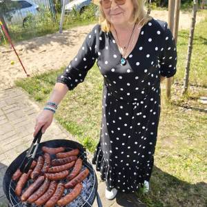 Uczestniczka ŚDS przerzuca kiełbaski na grillu