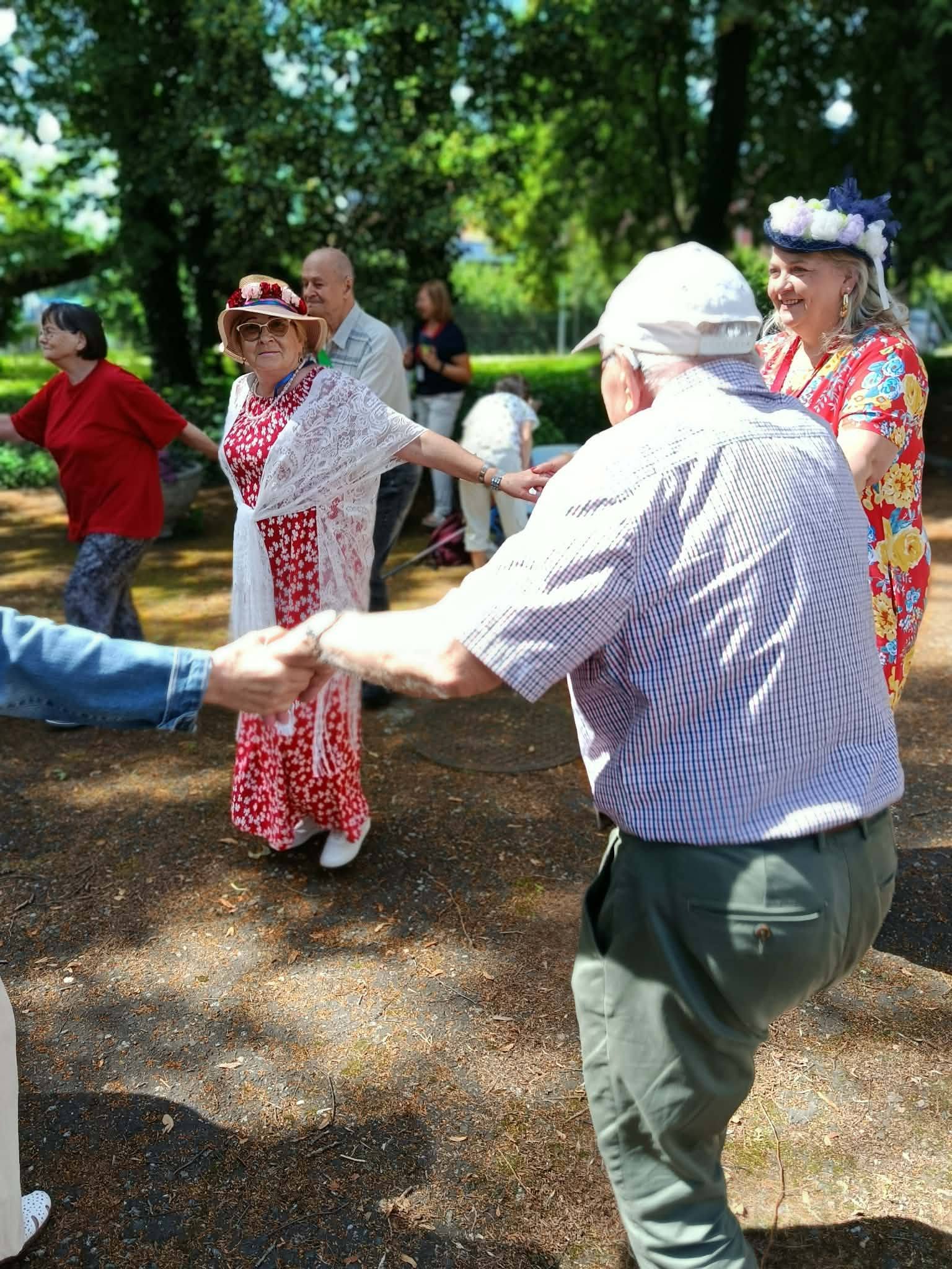 Uczestnicy ŚDS wraz z seniorami z dziennego domu pomocy tańczą w kółeczku trzymając się za ręce