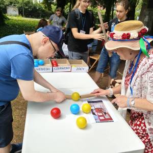 Uczestnicy ŚDS biorą udział w grze, stojąc przy stole