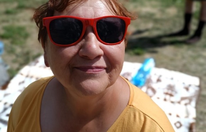 Starsza kobieta siedzi na plaży i pozuje do zdjęcia