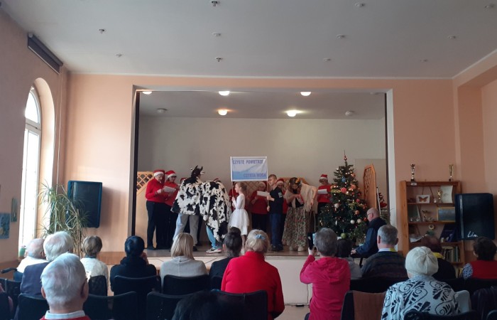 Kolędnicy i sztuka na scenie, różne przebrania, kolędnicy ubrani na czerwono i w czapkach Mikołaja 