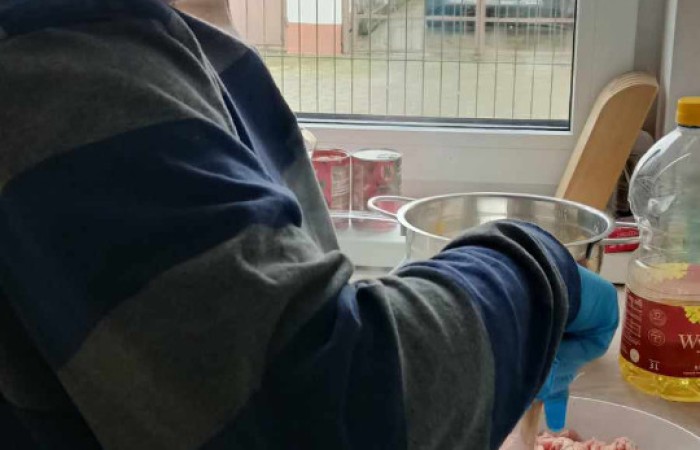 Starszy pan smaży mięso w czarnym garnku 