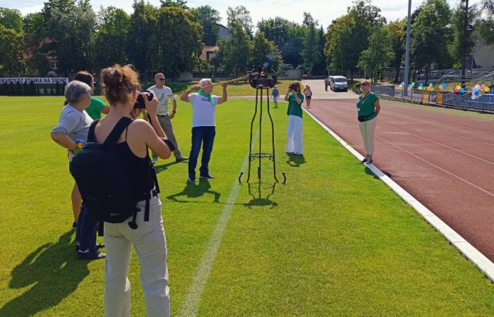Mężczyzna strzelający z łuku do celu, wokół niego grupa obserwatorów.