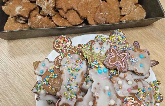  
Ozdobione lukrem posypkami i pisakami pierniki na talerzu, obok na blaszce czeka jeszcze więcej pierników 
