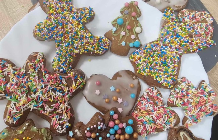 Ozdobione pierniki lukrem, pisakami i posypką na talerzu i tacce 