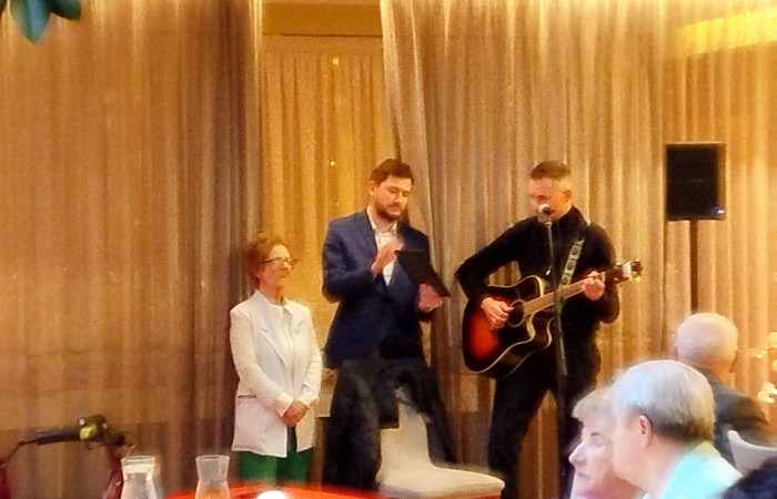 Uśmiechnięta kobieta pozująca do zdjęcia w dekoracyjnej ramce z napisem Sylwester ozdobionej kolorowymi dodatkami