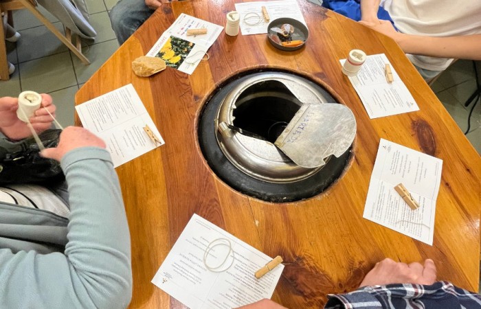 Uczestnicy ŚDS po nalaniu rozgrzanego wosku do formy na świeczkę, związują ją gumkami recepturkami aby utrwalić kształt świeczki