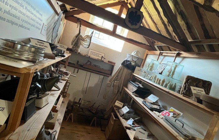 Pomieszczenie z regałami wypełnione jest starymi akcesoriami pszczelarskimi