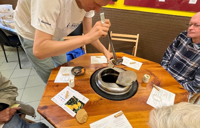 Uczestnicy ŚDS pobierają chochlą rozgrzany wosk z metalowej pojemnika, i przelewają go do gotowej formy na świeczkę