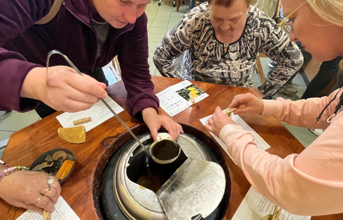 Uczestnicy ŚDS pobierają chochlą rozgrzany wosk z metalowej pojemnika, i przelewają go do gotowej formy na świeczkę