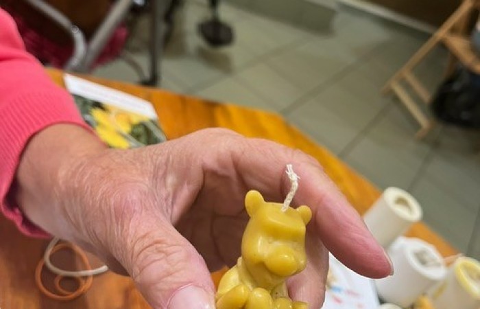 Uczestniczka ŚDS pokazuje swoją własnoręcznie robioną świeczkę w kształcie Kubusia Puchatka trzymającego serduszko.