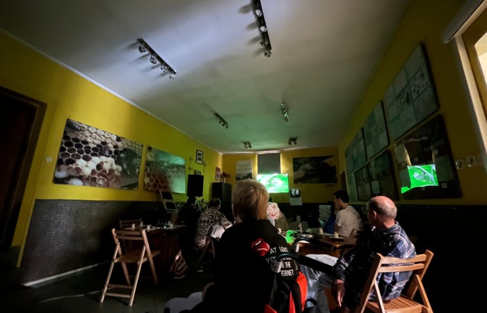 Uczestnicy ŚDS w zaciemniony pomieszczeniu oglądają film instruktażowy w muzeum pszczelarstwa