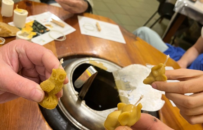 Uczestnicy ŚDS pokazują swoje świeczki z wosku. Widać świeczkę w kształcie sowy, i dwie świeczki w kształcie słoników